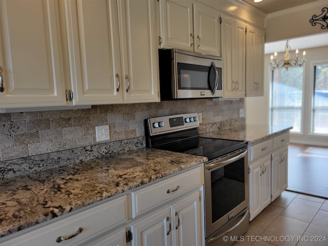 kitchen with decorative backsplash, appliances with stainless steel finishes, white cabinets, and light tile patterned floors