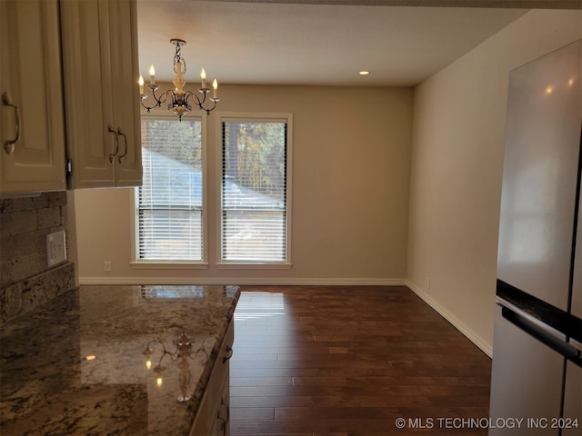 kitchen featuring hanging light fixtures, a chandelier, stainless steel refrigerator, dark hardwood / wood-style floors, and light stone counters