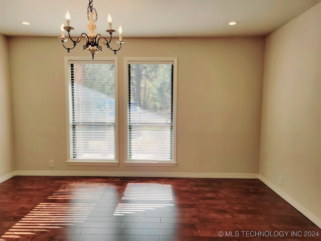 unfurnished room featuring a notable chandelier and dark hardwood / wood-style floors