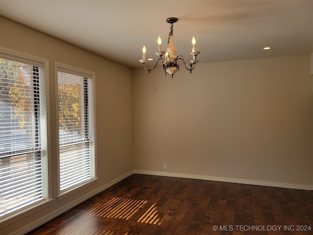 unfurnished room featuring a notable chandelier and dark hardwood / wood-style floors