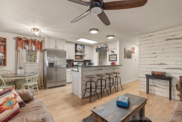 living room featuring light hardwood / wood-style floors, a textured ceiling, and ceiling fan