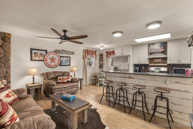 living room featuring light hardwood / wood-style floors, sink, and ceiling fan