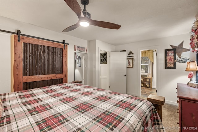 carpeted bedroom with ceiling fan and a barn door