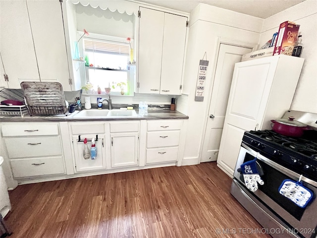 kitchen with stainless steel range with gas stovetop, sink, white cabinets, and dark wood-type flooring