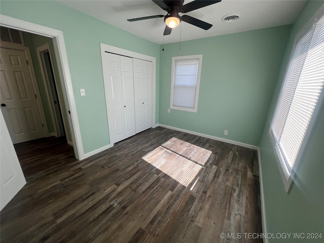 unfurnished bedroom featuring dark wood-type flooring, a closet, and ceiling fan