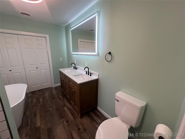 bathroom featuring wood-type flooring, a tub, vanity, and toilet