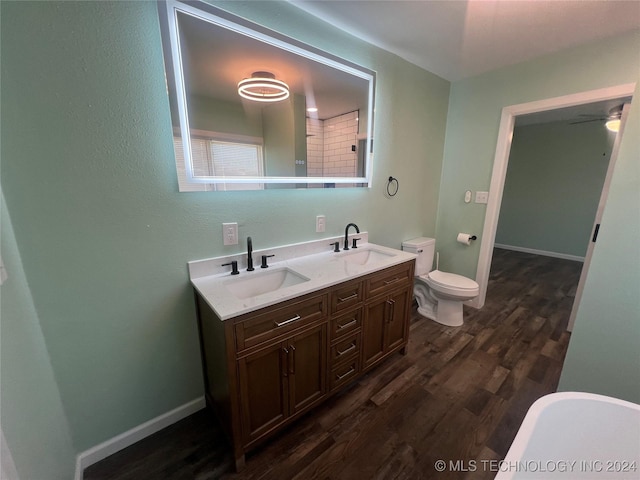 bathroom featuring ceiling fan, hardwood / wood-style floors, vanity, toilet, and a bathing tub