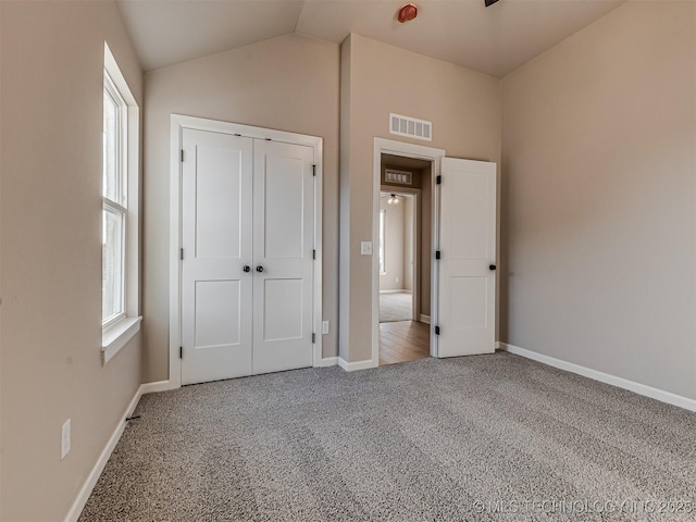 unfurnished bedroom with carpet, lofted ceiling, and a closet