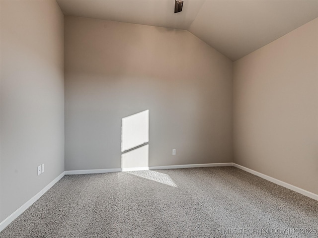 carpeted empty room featuring vaulted ceiling