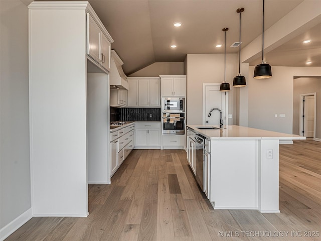 kitchen with backsplash, stainless steel appliances, sink, a center island with sink, and white cabinets