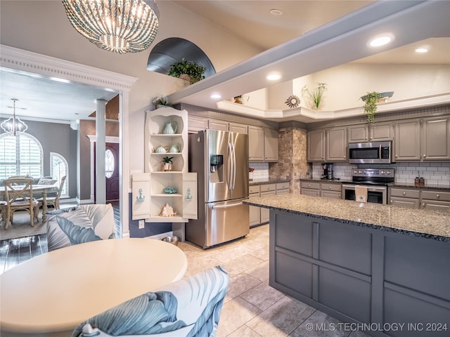 kitchen with decorative backsplash, hanging light fixtures, vaulted ceiling, gray cabinetry, and stainless steel appliances