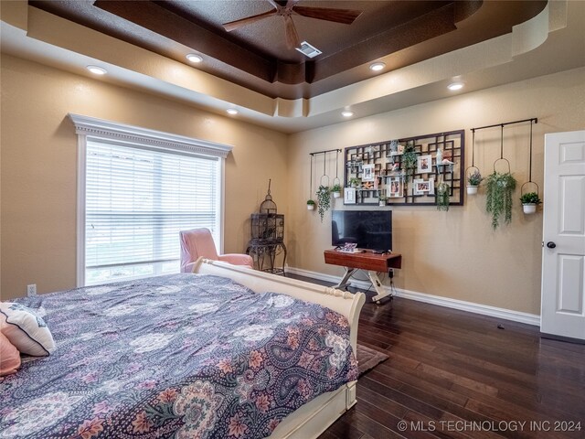 bedroom featuring ceiling fan, dark wood-type flooring, and a raised ceiling