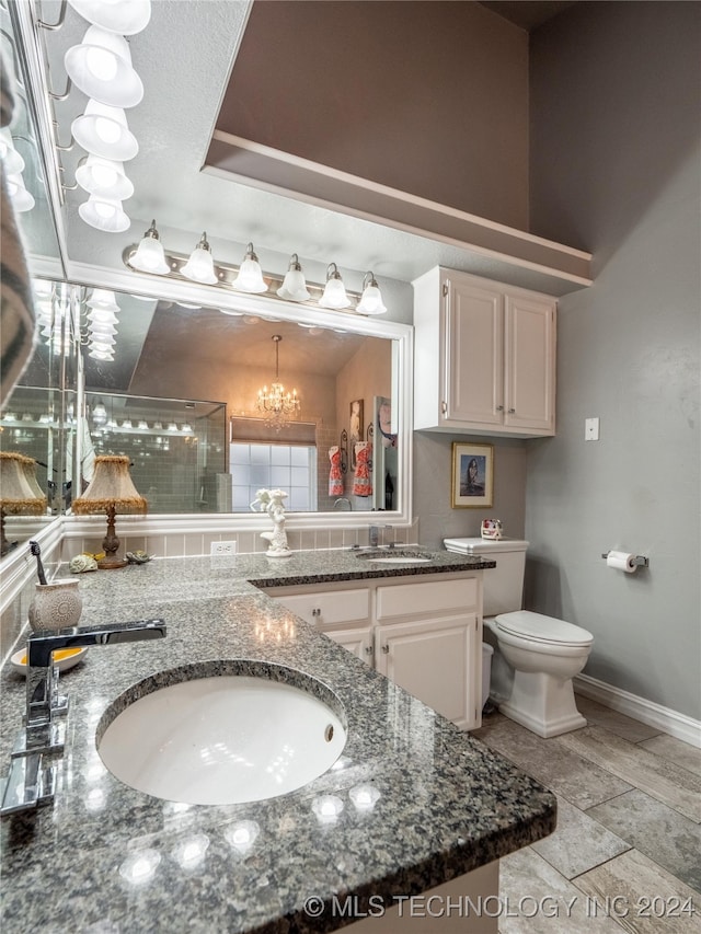 bathroom featuring vanity, toilet, a notable chandelier, and walk in shower