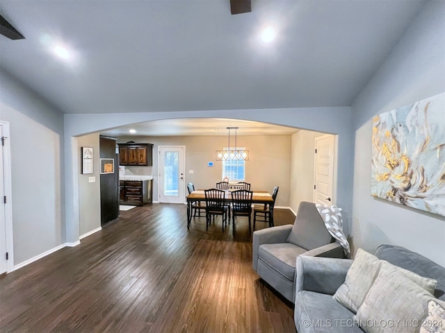 living room featuring dark hardwood / wood-style floors, a chandelier, and vaulted ceiling