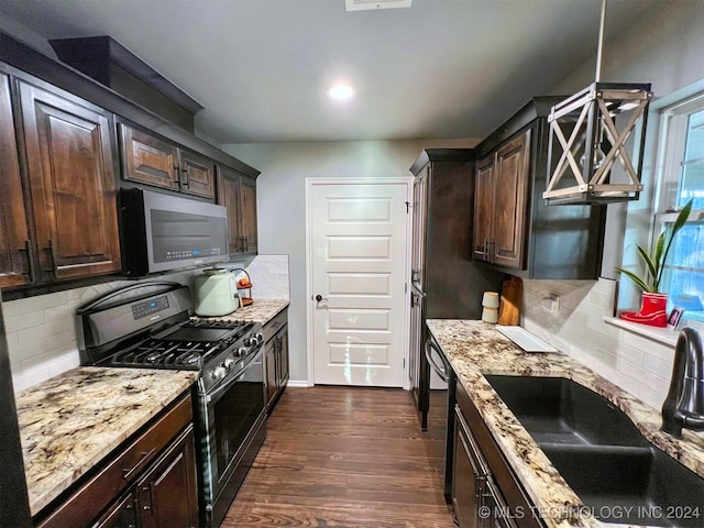 kitchen featuring light stone countertops, appliances with stainless steel finishes, dark hardwood / wood-style floors, and backsplash