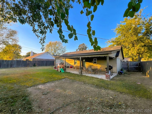 back of house with a patio area and a lawn