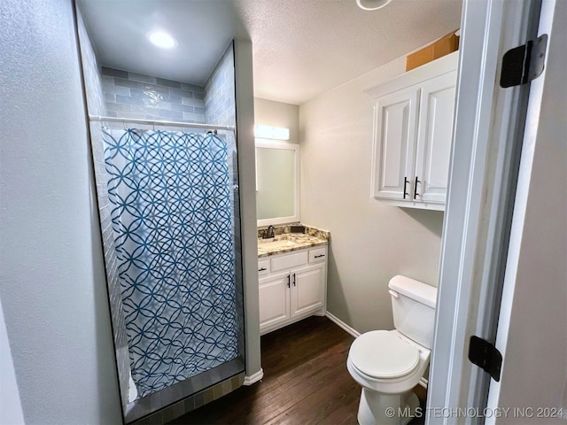 bathroom with hardwood / wood-style flooring, toilet, curtained shower, vanity, and a textured ceiling