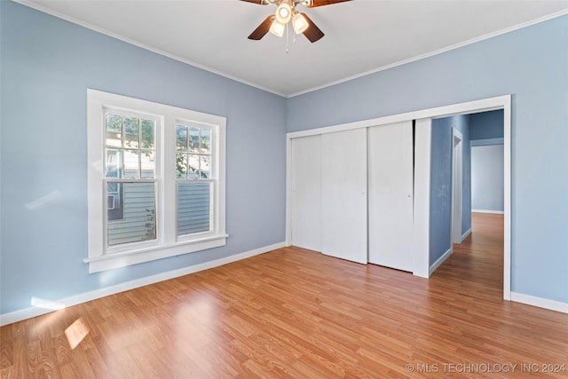 unfurnished bedroom featuring ceiling fan, crown molding, light hardwood / wood-style flooring, and a closet
