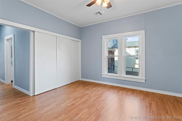 unfurnished bedroom featuring ceiling fan, a closet, ornamental molding, and light hardwood / wood-style flooring