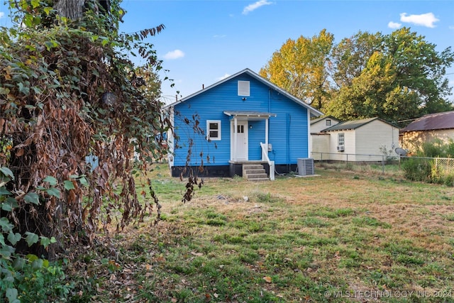 rear view of property featuring a lawn and cooling unit