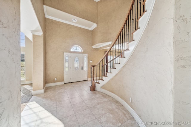 foyer entrance with a towering ceiling, a wealth of natural light, and ornamental molding