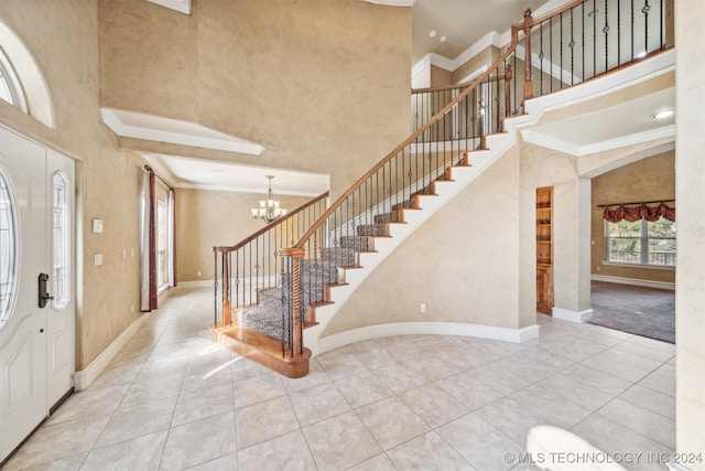 tiled entryway with crown molding, a high ceiling, and an inviting chandelier