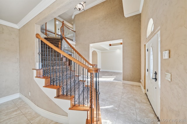 tiled foyer featuring crown molding and a high ceiling