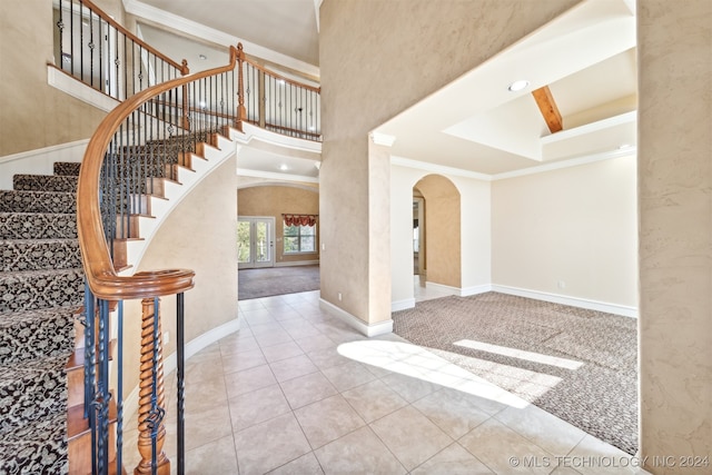 carpeted foyer with ornamental molding and a high ceiling