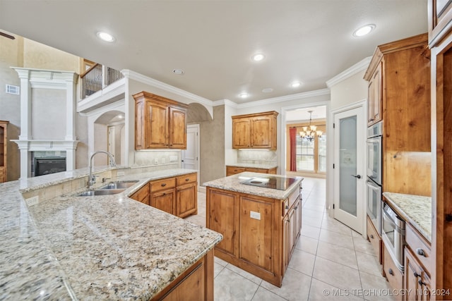 kitchen featuring sink, crown molding, light stone counters, a fireplace, and a kitchen island