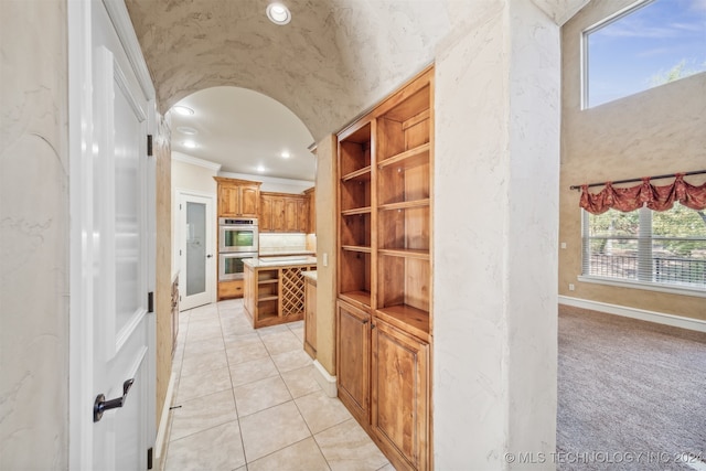 corridor with crown molding, light tile patterned flooring, and vaulted ceiling