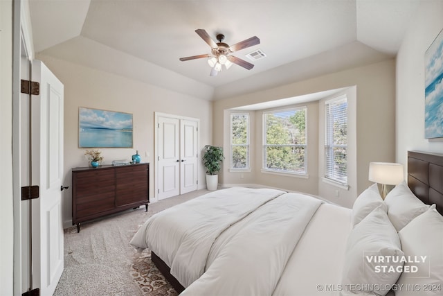 bedroom featuring ceiling fan, a raised ceiling, and light carpet