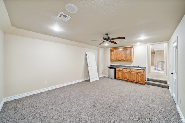 kitchen with dishwasher, sink, ceiling fan, light carpet, and a textured ceiling