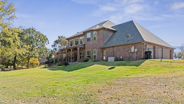 rear view of house featuring central air condition unit and a lawn