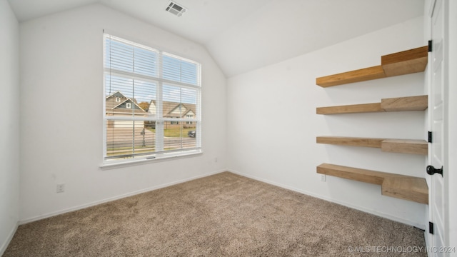 carpeted spare room featuring vaulted ceiling