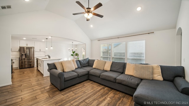 living room featuring high vaulted ceiling, sink, hardwood / wood-style flooring, and ceiling fan with notable chandelier