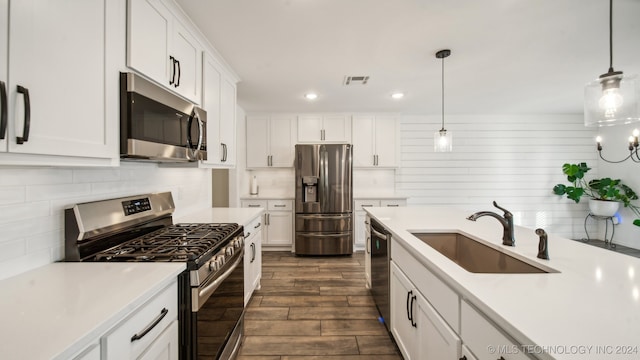 kitchen with dark wood-type flooring, stainless steel appliances, sink, and pendant lighting