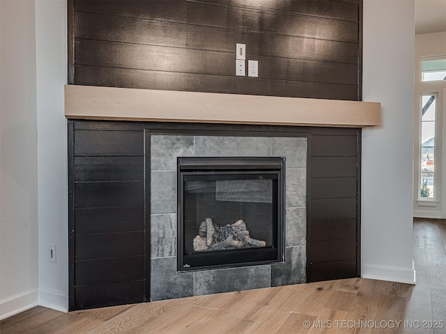 details featuring hardwood / wood-style flooring and a tiled fireplace