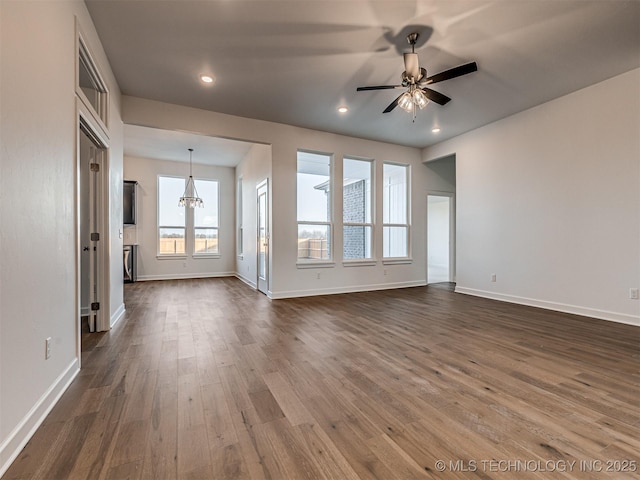 unfurnished living room with dark hardwood / wood-style flooring and ceiling fan with notable chandelier