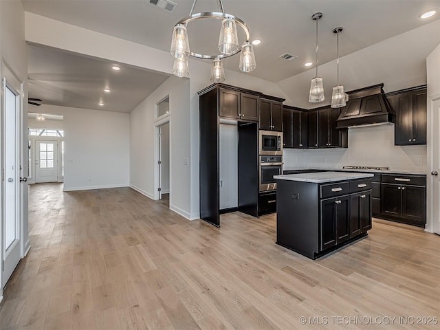 kitchen with decorative light fixtures, a center island, custom range hood, and appliances with stainless steel finishes