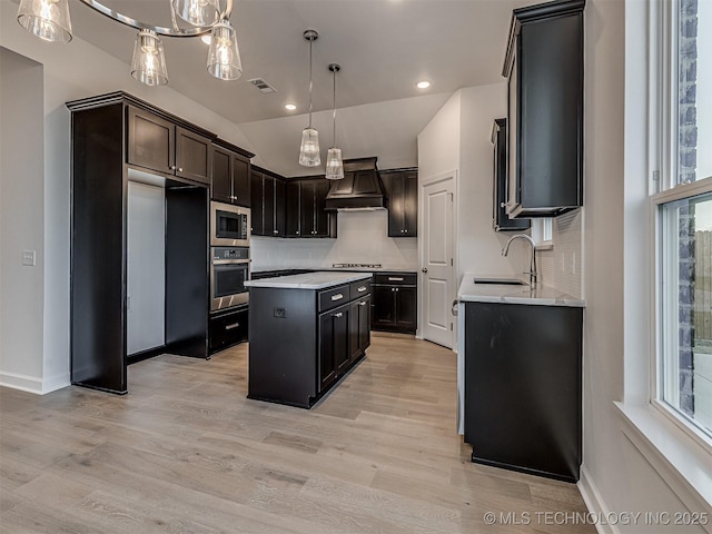 kitchen with sink, a wealth of natural light, a kitchen island, custom range hood, and stainless steel appliances