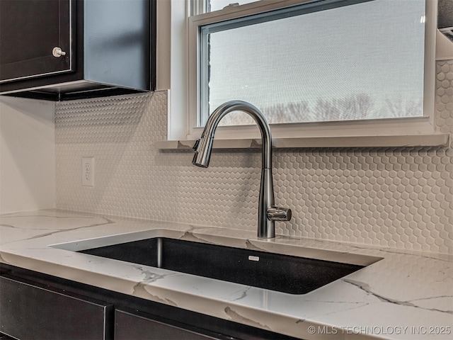 room details featuring light stone countertops and sink