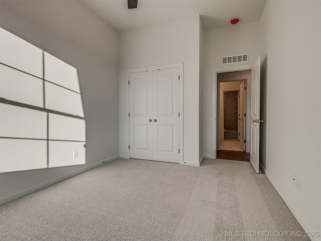 unfurnished bedroom with light colored carpet, a high ceiling, and a closet