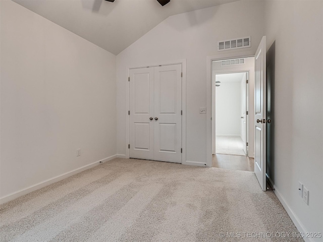 unfurnished bedroom with ceiling fan, a closet, light carpet, and lofted ceiling