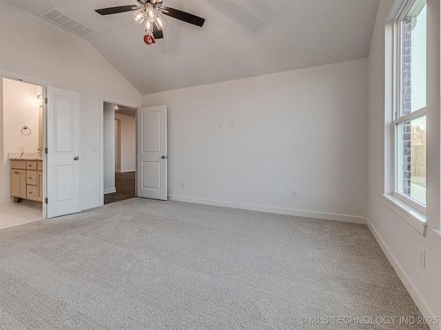 unfurnished bedroom with ceiling fan, ensuite bathroom, lofted ceiling, and light carpet