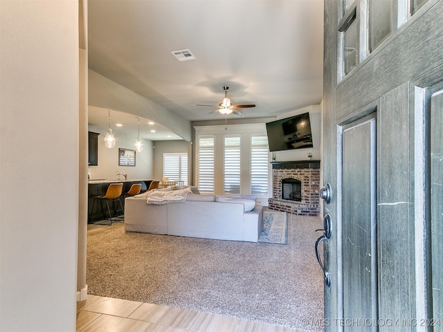 carpeted living room featuring ceiling fan and a fireplace