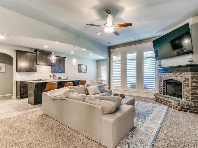 carpeted living room featuring ceiling fan and a fireplace