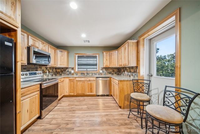 kitchen featuring light hardwood / wood-style flooring, tasteful backsplash, appliances with stainless steel finishes, and sink