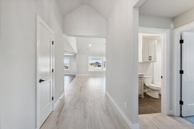 hallway with vaulted ceiling and light hardwood / wood-style flooring