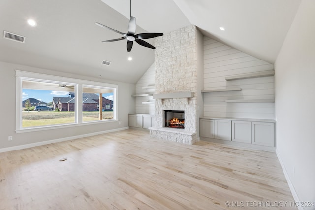 unfurnished living room with a stone fireplace, high vaulted ceiling, light hardwood / wood-style floors, and ceiling fan