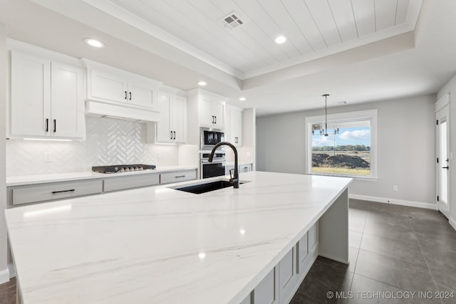 kitchen featuring hanging light fixtures, appliances with stainless steel finishes, white cabinetry, dark tile patterned flooring, and light stone counters